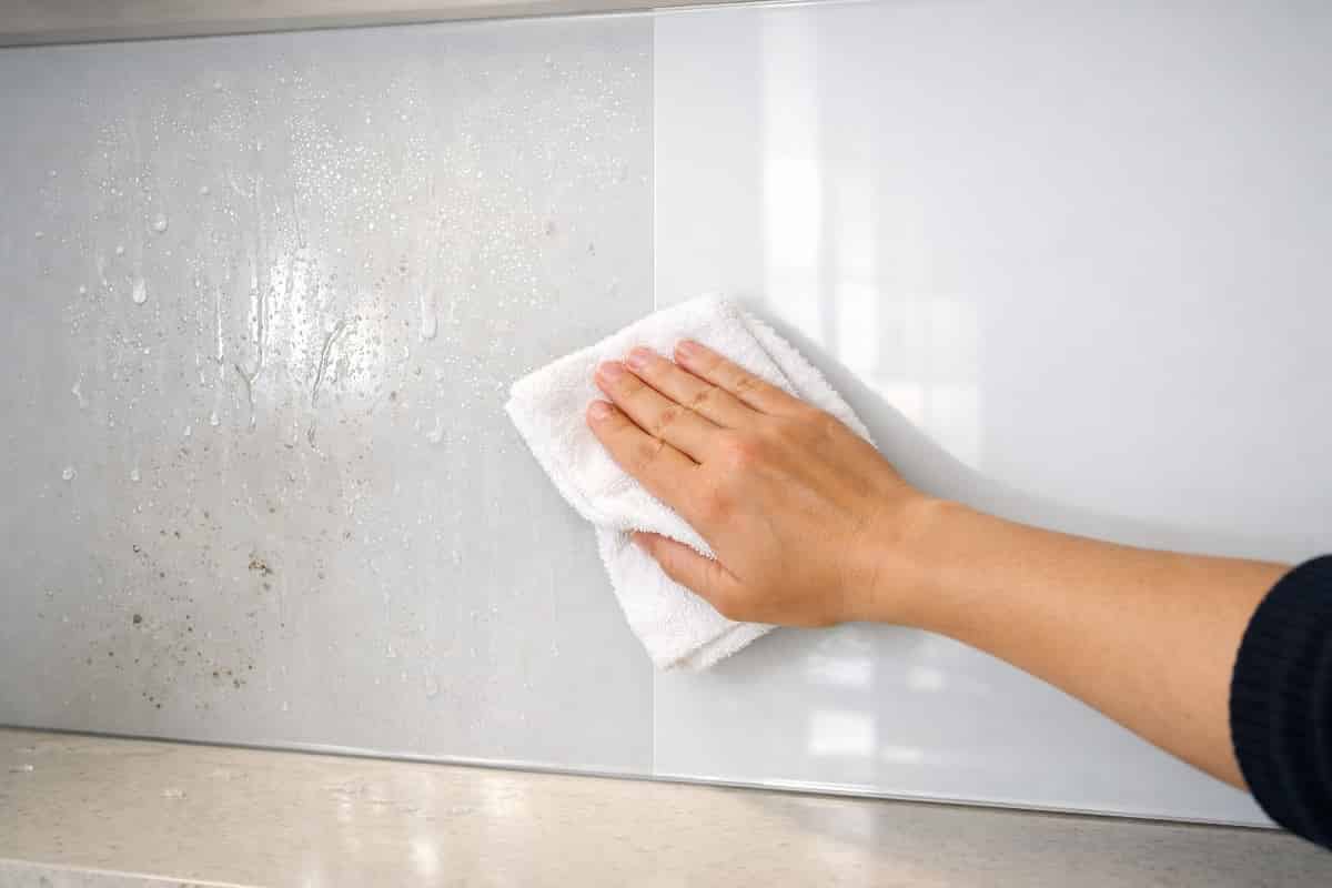 Nettoyage d’une crédence en verre dans une cuisine moderne avec un chiffon microfibre